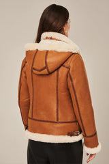 Brown shearling jacket with white fur lining worn by a person on a neutral background