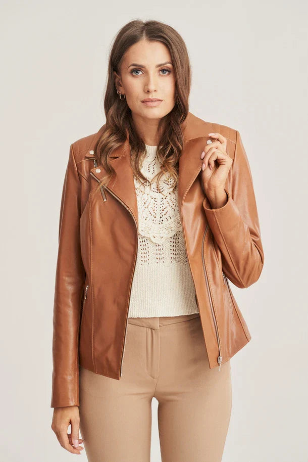 Woman wearing a brown leather jacket over a white top and beige pants on a light background