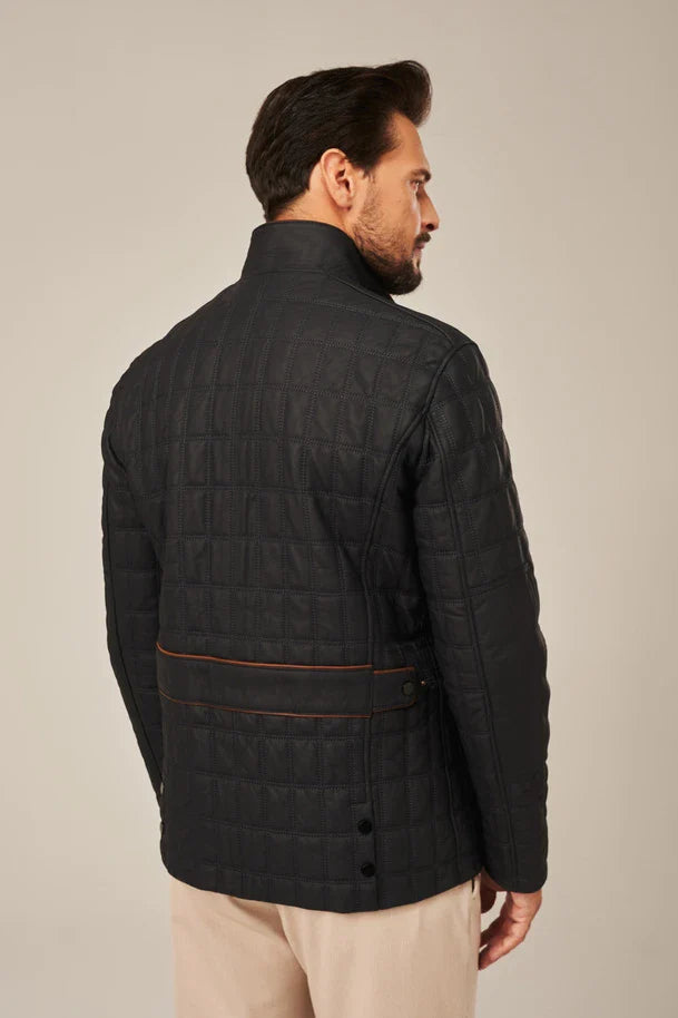 Man wearing a black quilted jacket on a beige background